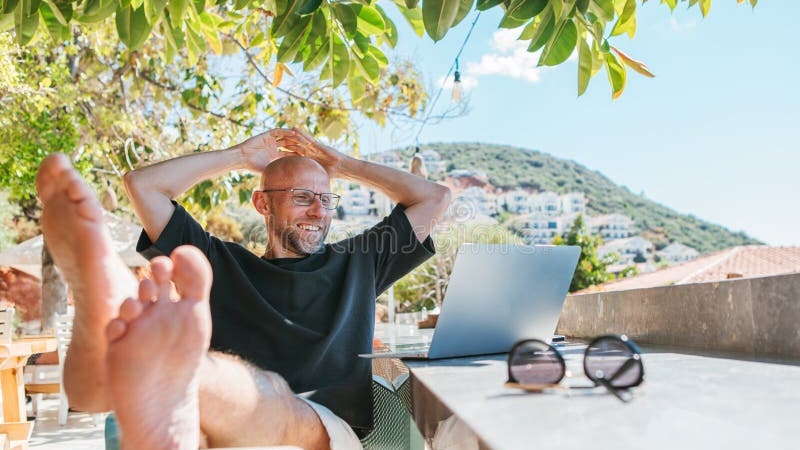 Professional enjoying freedom lifestyle on a sunlit terrace, laptop closed, looking content and present